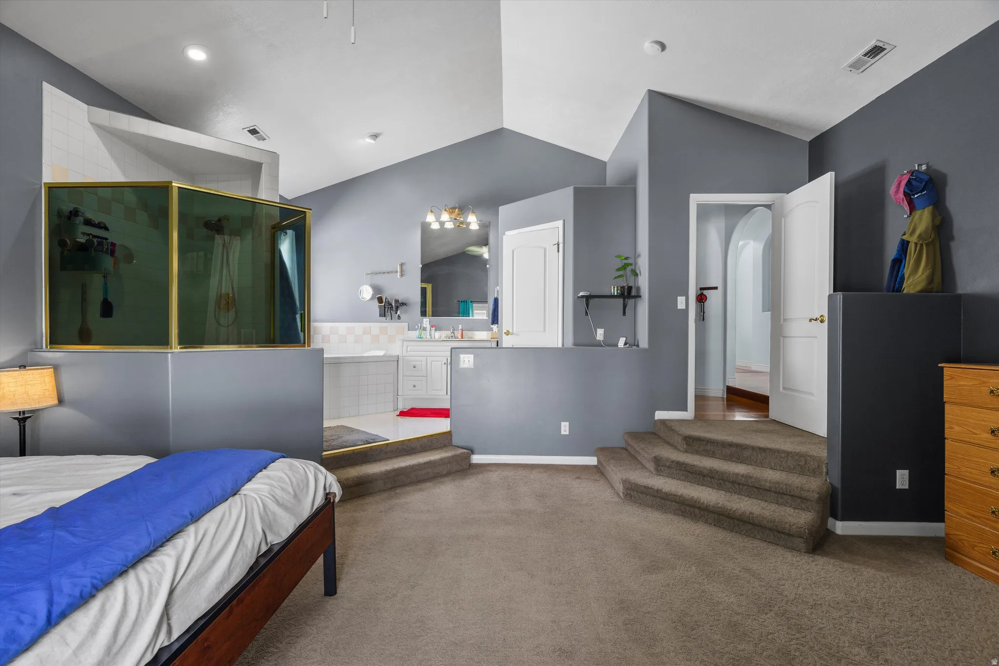 Carpeted bedroom with lofted ceiling and arched walkways
