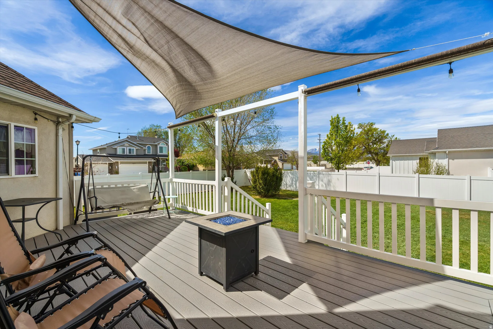 Composite deck with an outdoor fire pit, a fenced backyard, and a residential view
