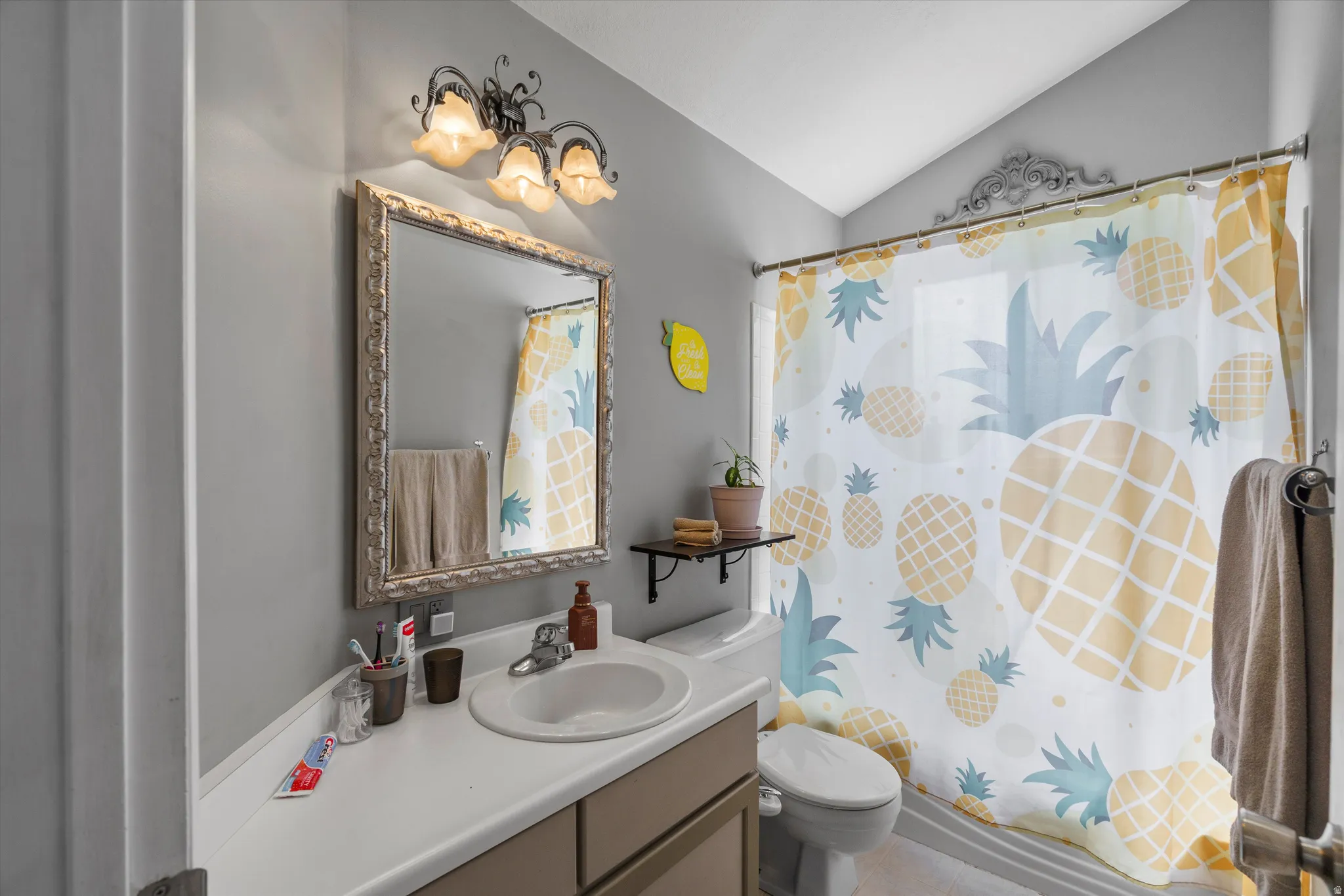 Bathroom with vanity, a shower with shower curtain, and vaulted ceiling