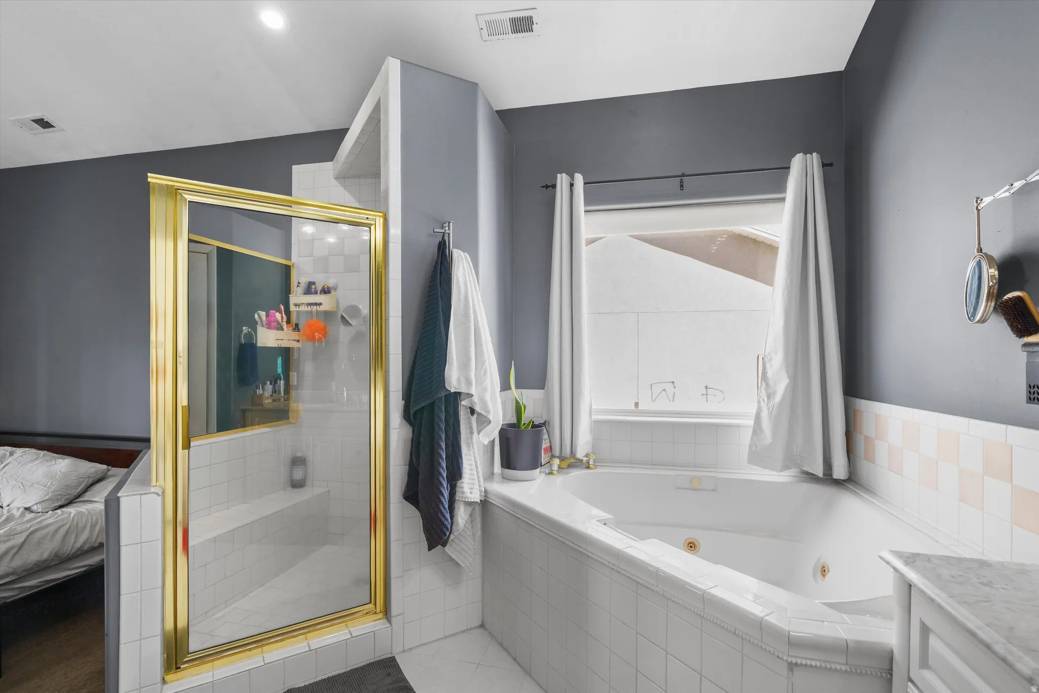 Ensuite bathroom featuring a shower stall, a jetted tub, and vanity