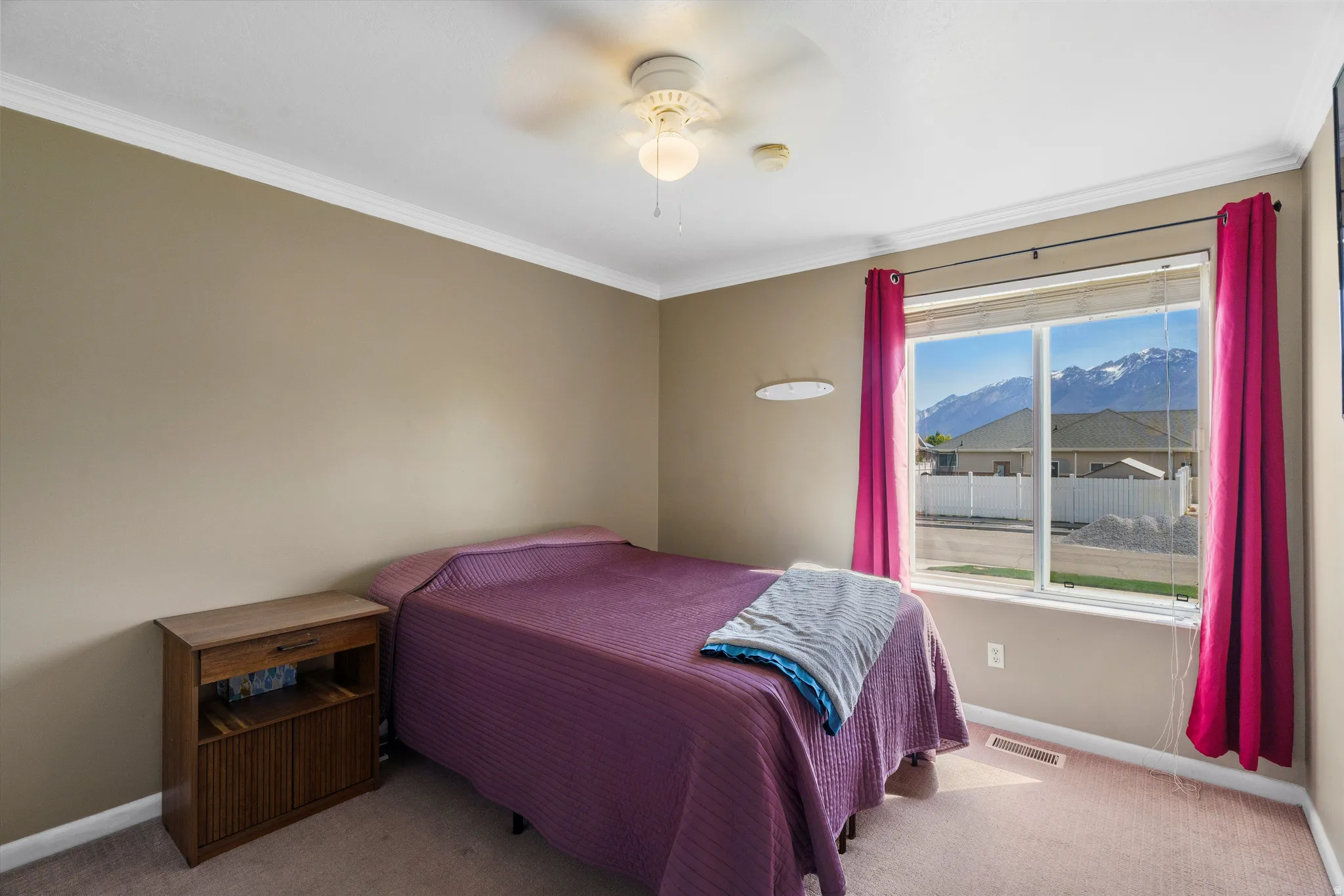 Bedroom featuring a mountain view, light carpet, crown molding, and ceiling fan