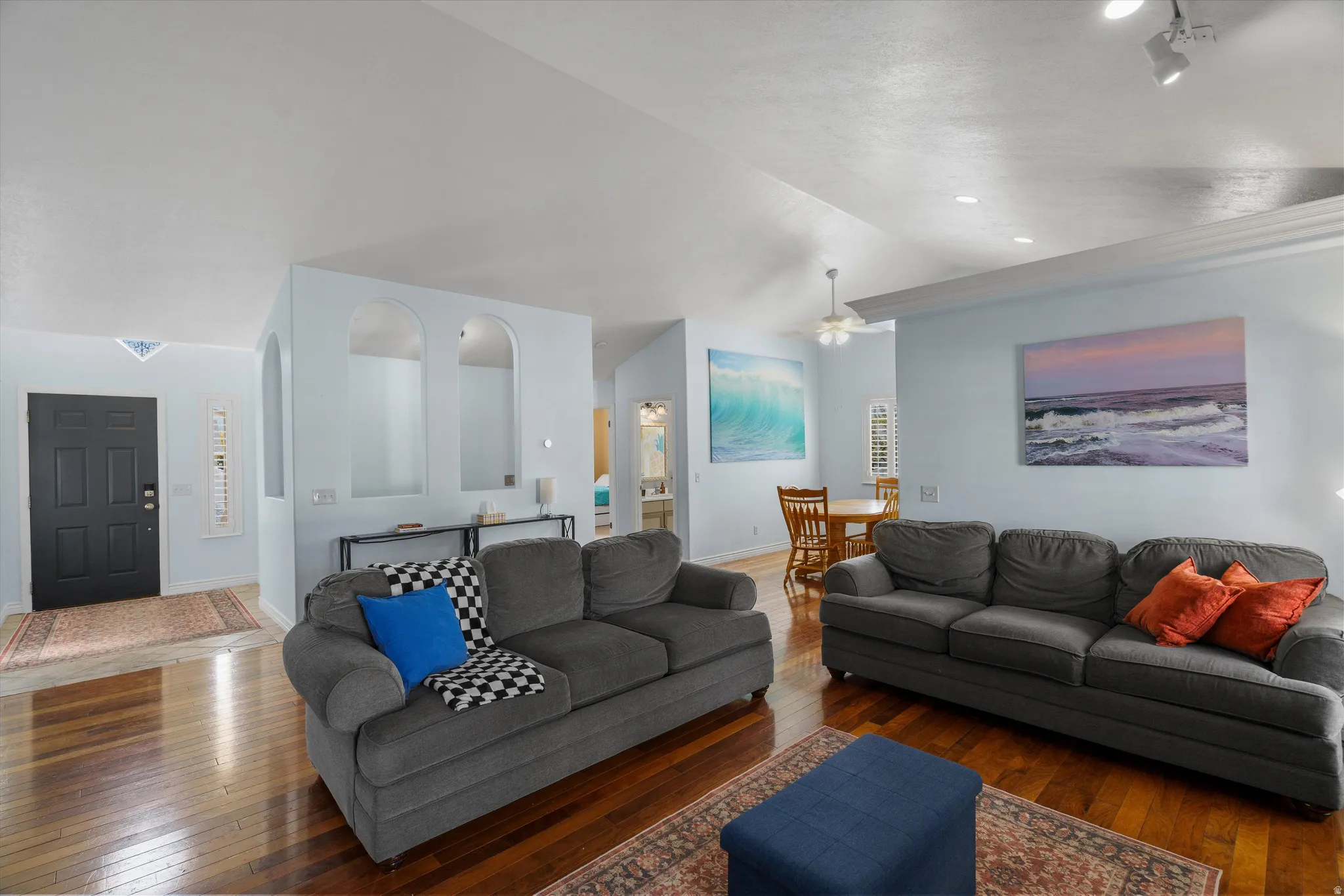 Living room featuring wood flooring, lofted ceiling, and a ceiling fan
