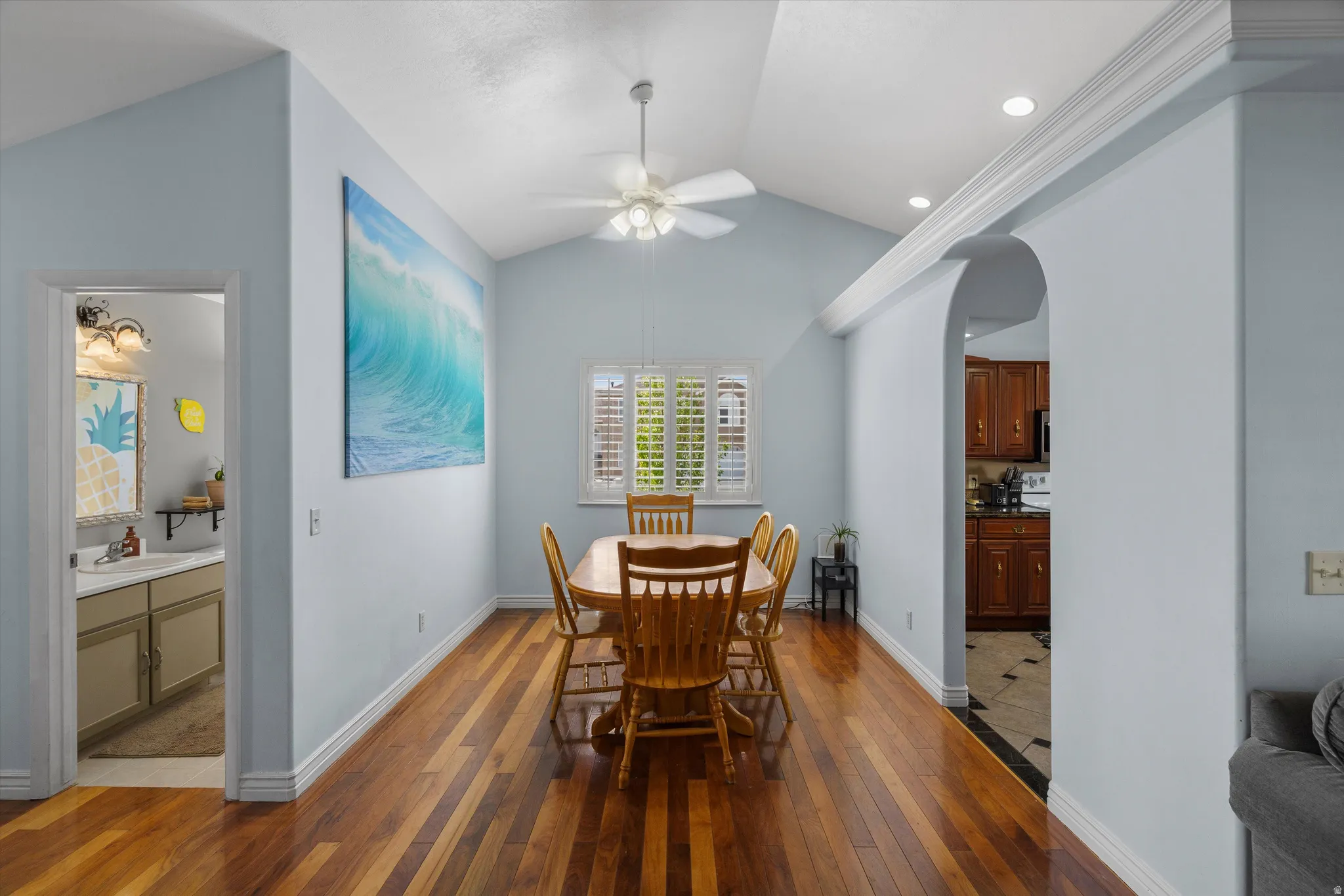 Dining area featuring dark wood flooring, a ceiling fan, arched walkways, and recessed lighting