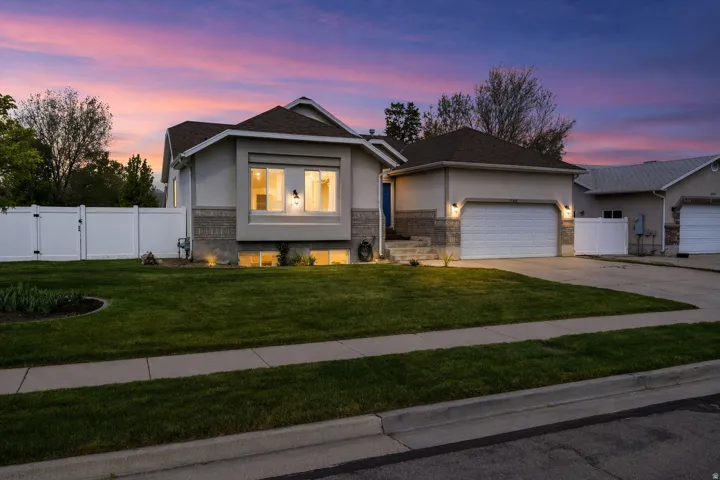 View of front facade with a gate, stucco siding, a garage, and driveway