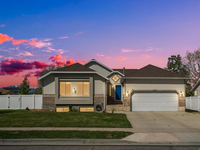 Ranch-style residence featuring a two-car garage, partial brick facade, and a vibrant blue entry door