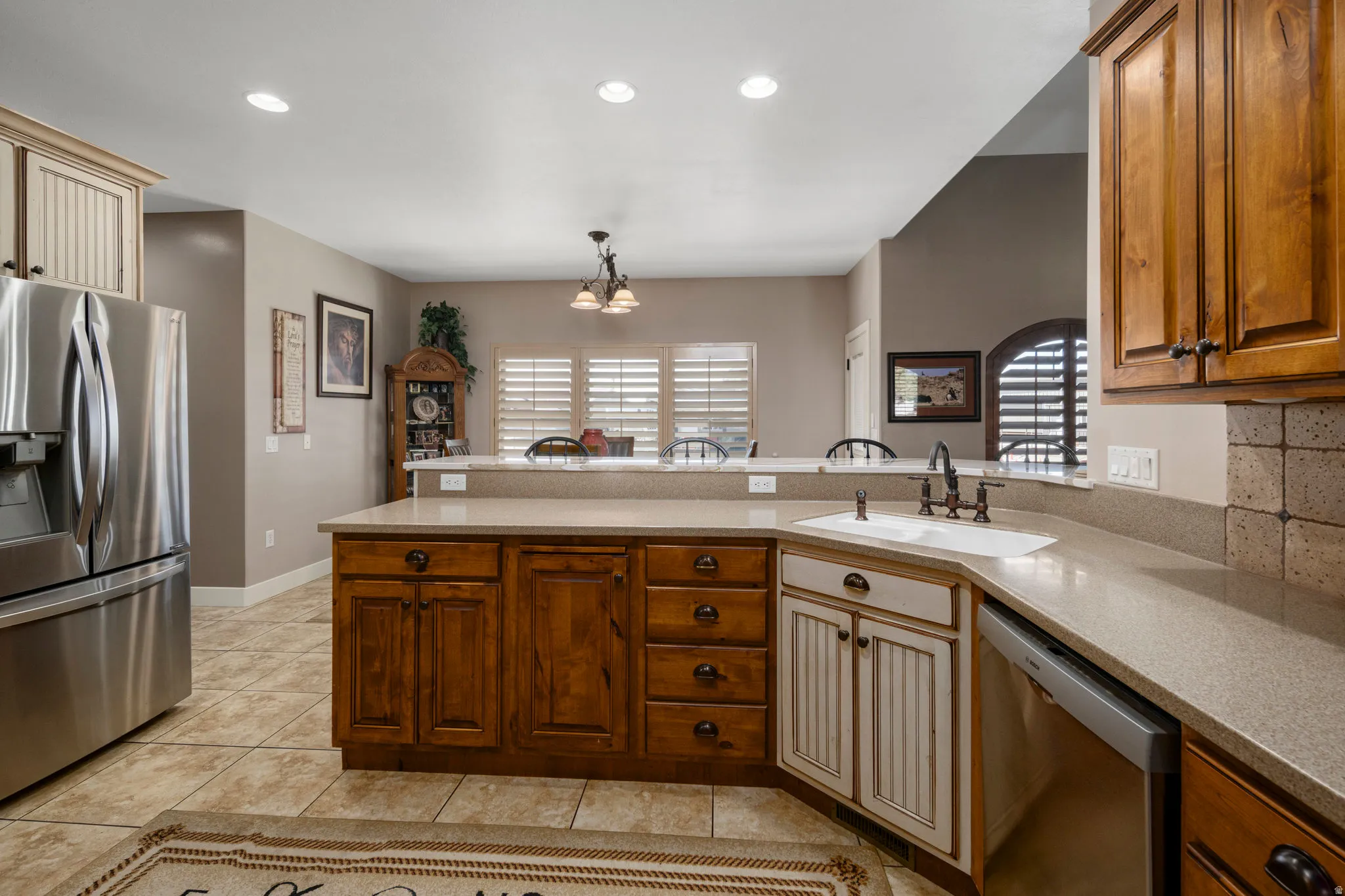 Kitchen with stainless steel appliances, a peninsula, a chandelier, and light stone countertops