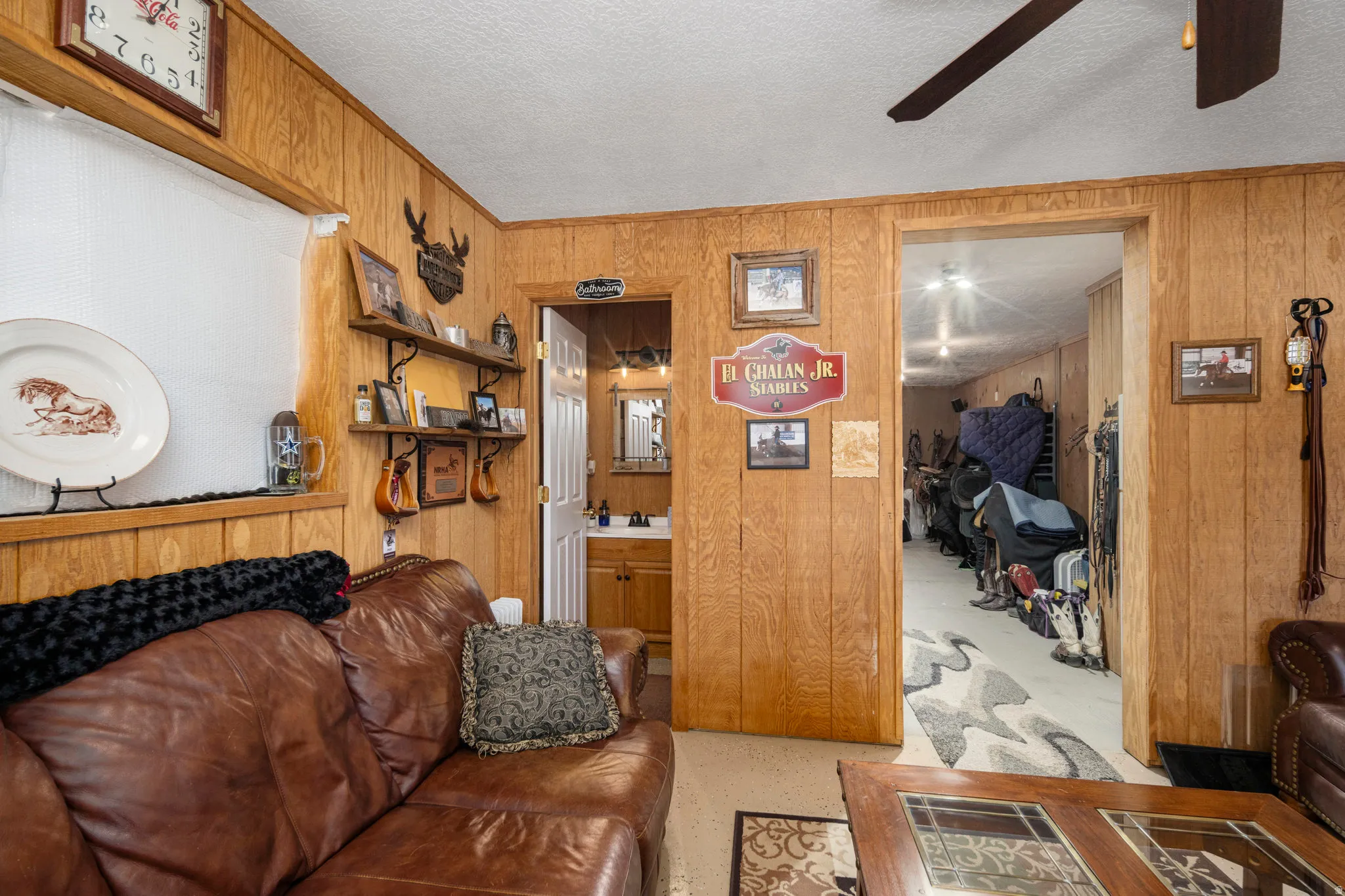 Living room featuring a textured ceiling, wooden walls, and a ceiling fan