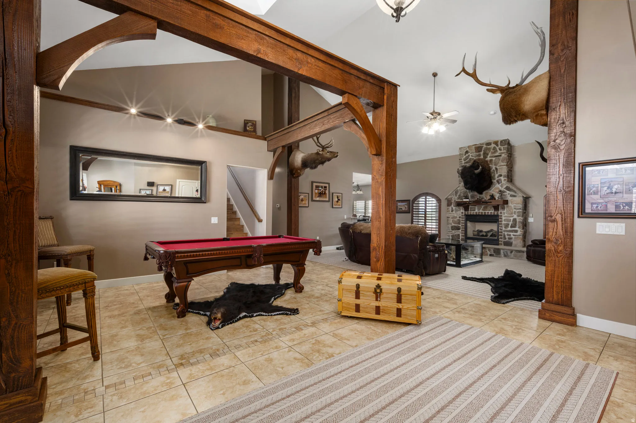 Playroom with a stone fireplace, lofted ceiling, light tile patterned floors, ceiling fan, and billiards