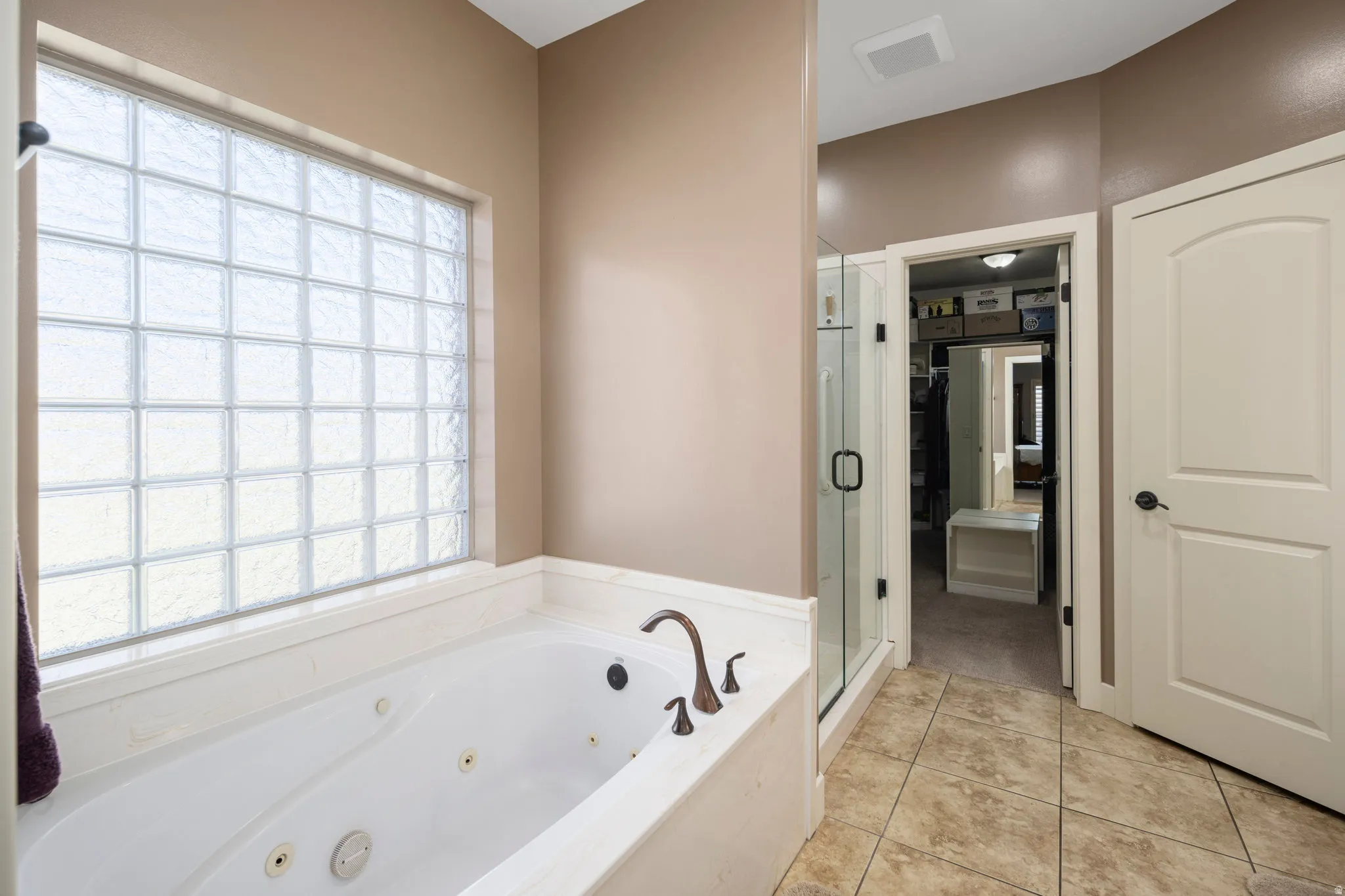 Bathroom featuring a shower stall, a whirlpool tub, and light tile patterned flooring