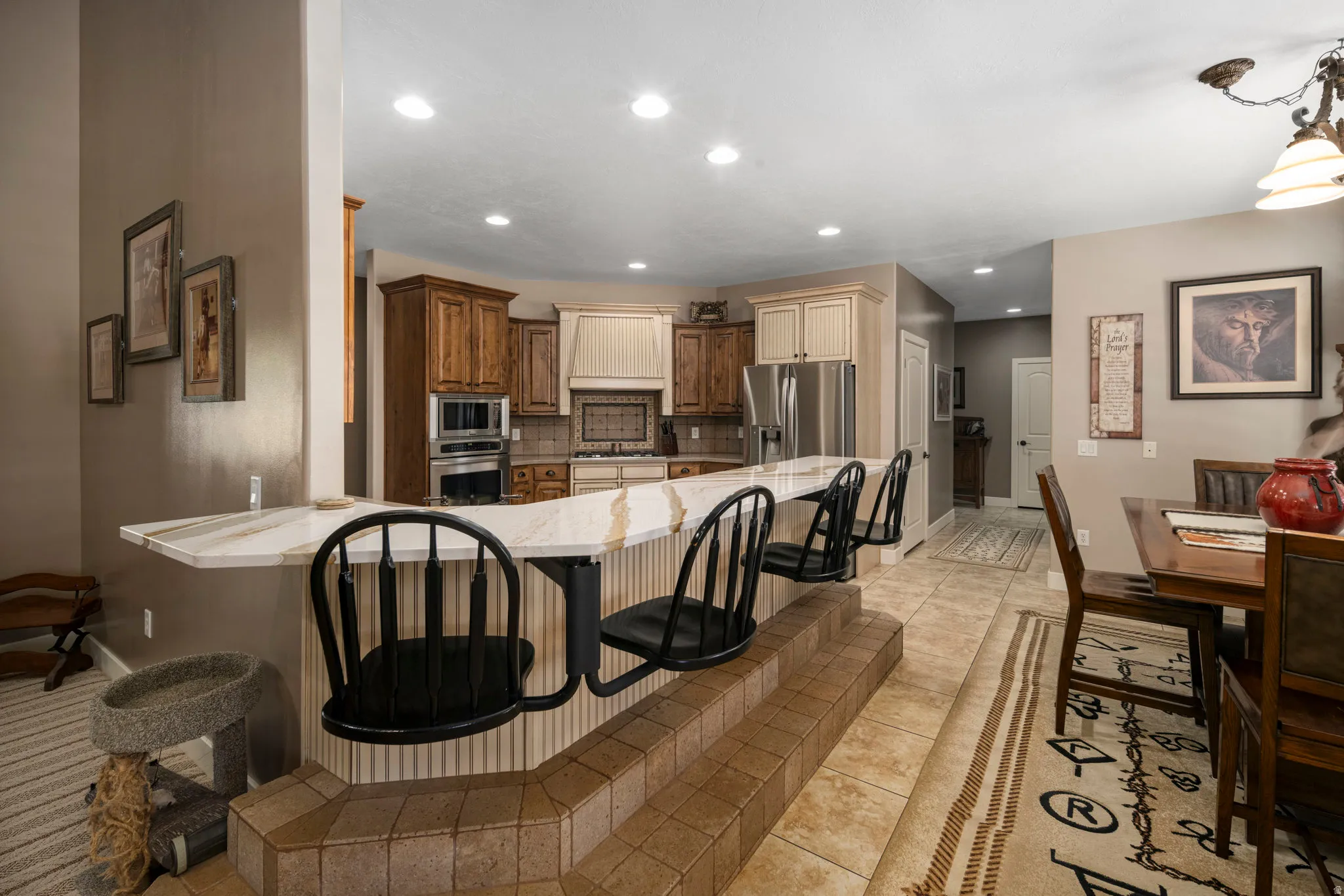 Kitchen featuring a kitchen breakfast bar, stainless steel appliances, light stone counters, recessed lighting, and tasteful backsplash