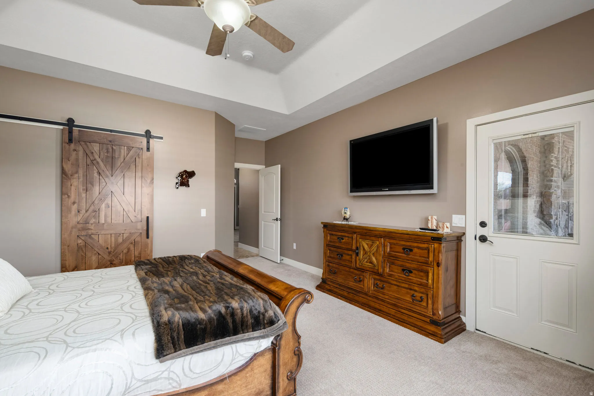 Bedroom featuring a barn door, light carpet, and ceiling fan