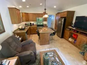 Kitchen featuring wood finish cabinetry, stainless steel appliances, light countertops, and vaulted ceiling