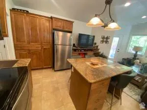 Kitchen with wood finish cabinets, a kitchen bar, stainless steel appliances, and light stone counters