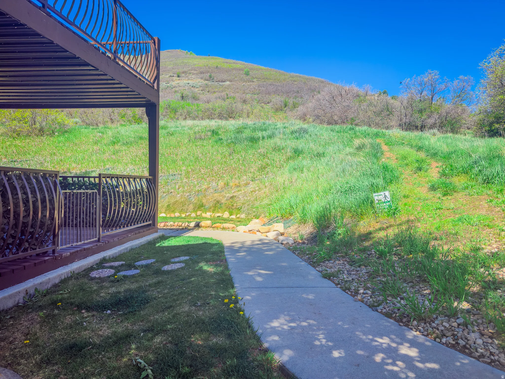 Ground-level patio with decorative metal railing and concrete walkway