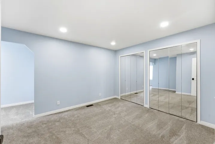 Bedroom in Midway condo for sale with mirrored closet doors, carpet flooring, and attached flex space