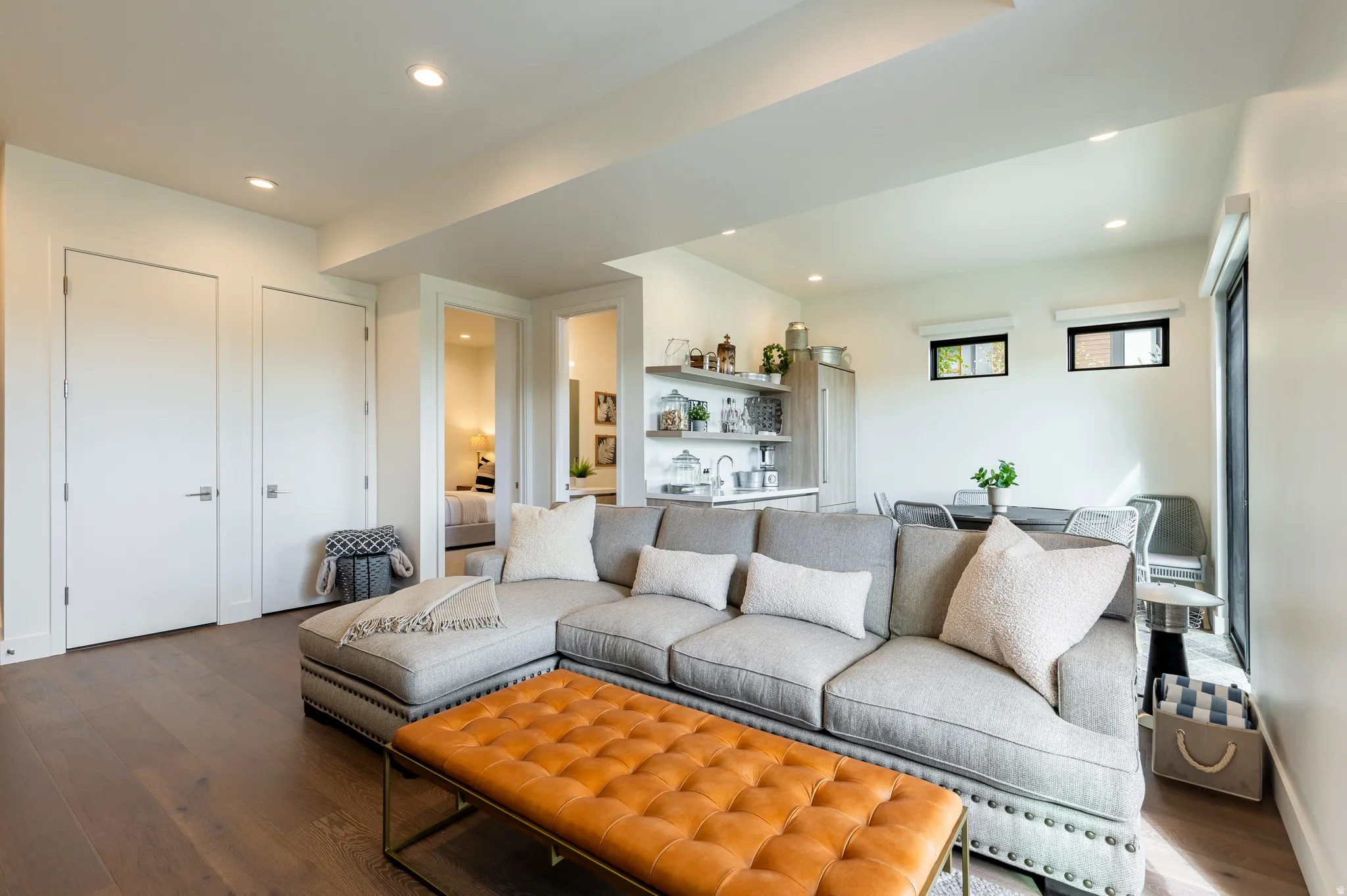 Living area with dark wood-style floors, bar with sink, and recessed lighting