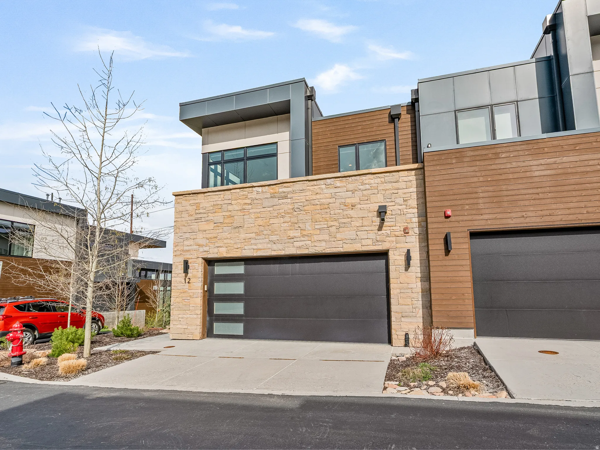 Contemporary townhome with stone siding, concrete driveway, and a garage