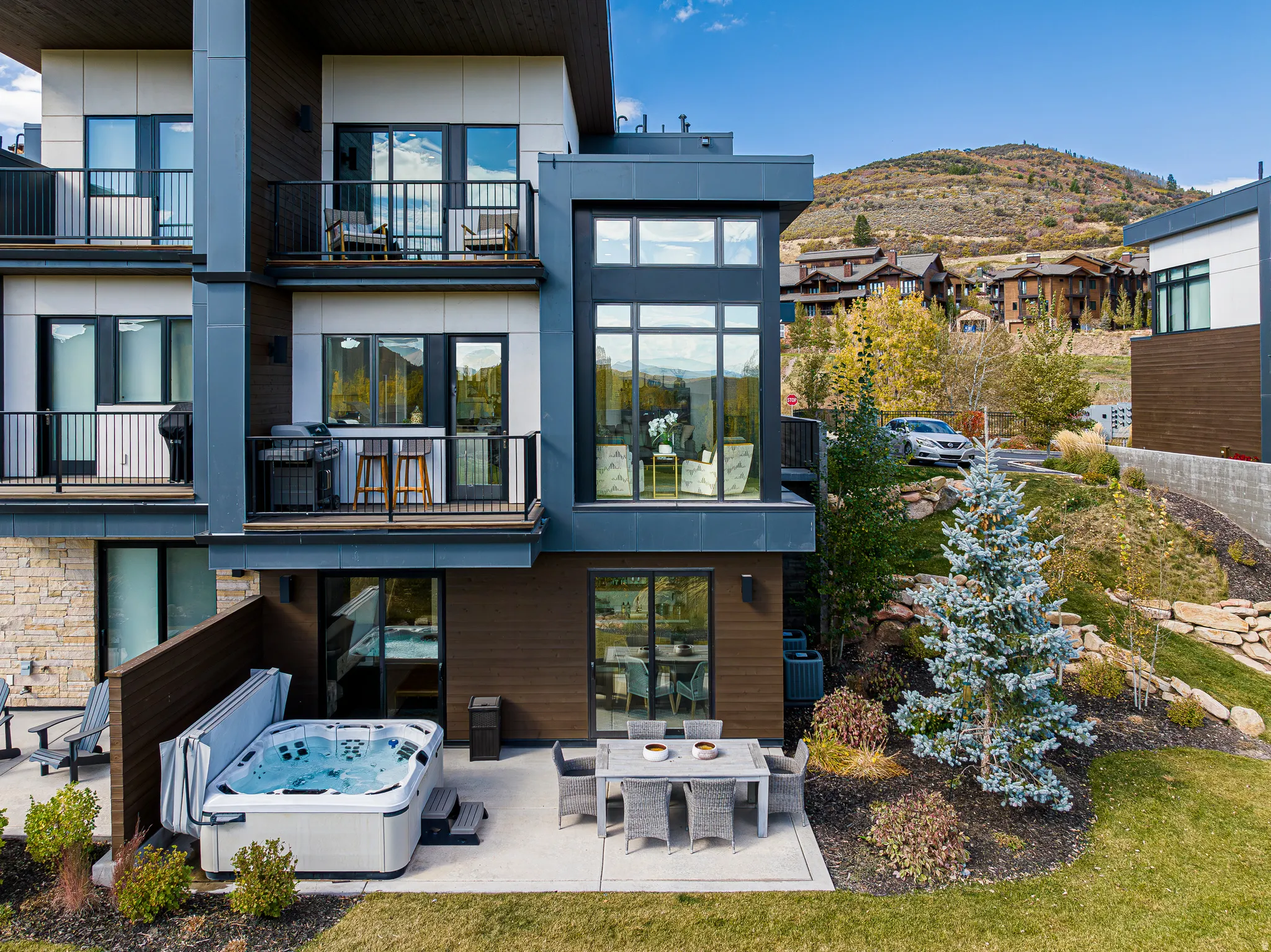 Rear view of house featuring a balcony, a mountain view, a hot tub, a patio area, and outdoor dining space