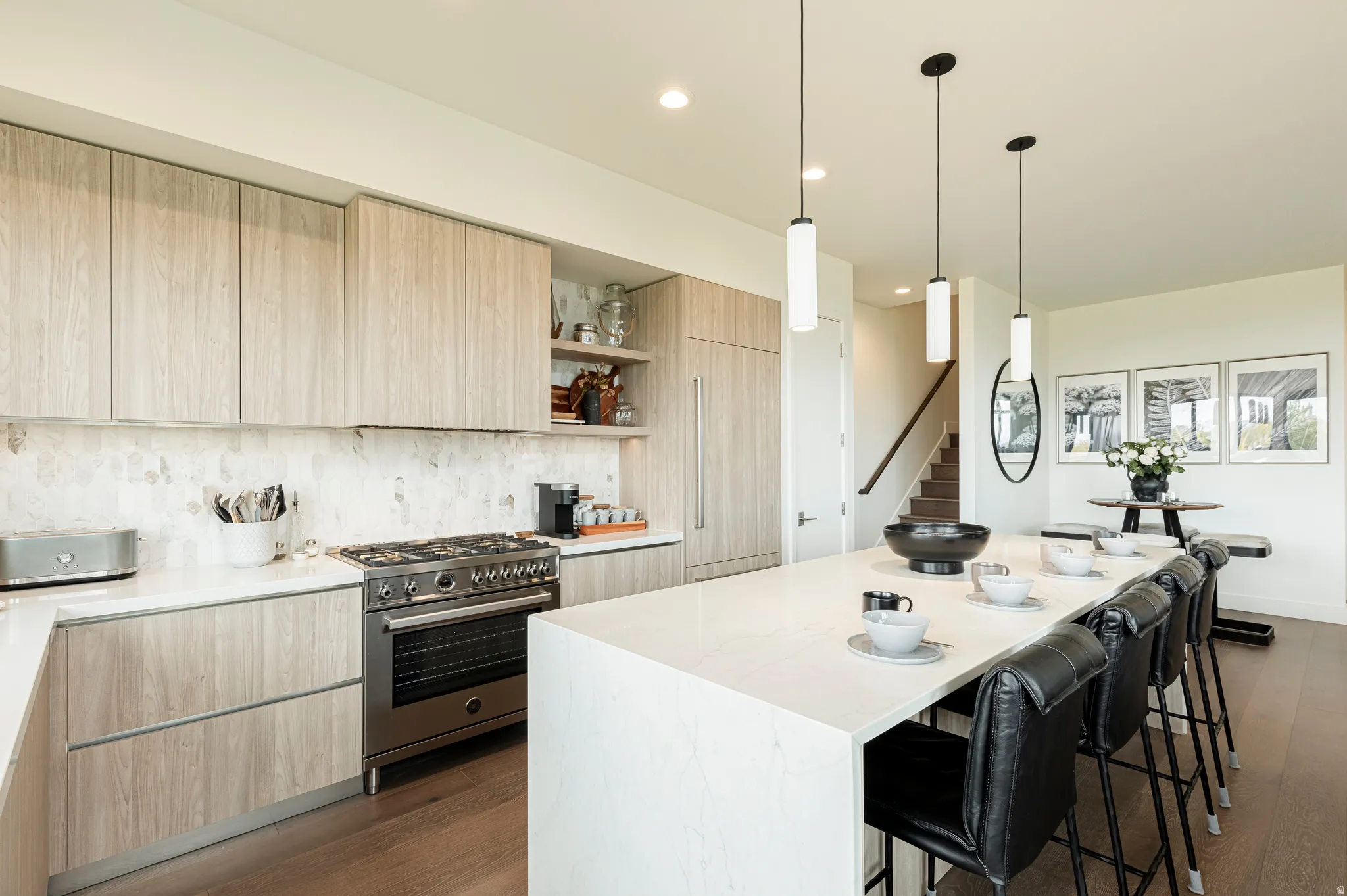 Kitchen with light wood finish cabinetry, high end range, modern cabinets, a breakfast bar, and light stone countertops