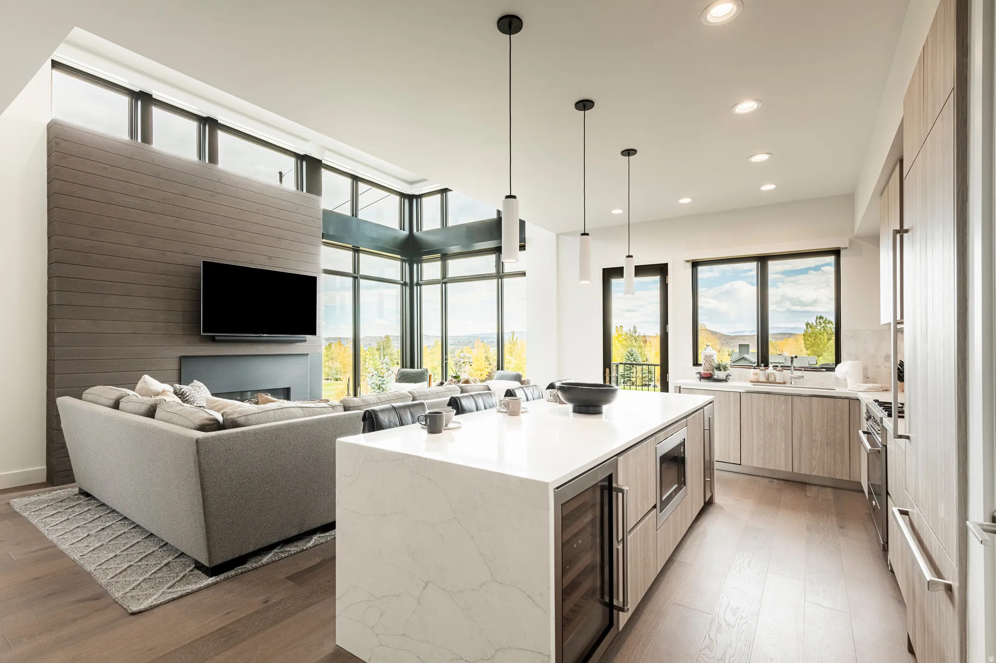 Kitchen with modern cabinets, a kitchen island, open floor plan, light stone counters, and beverage cooler