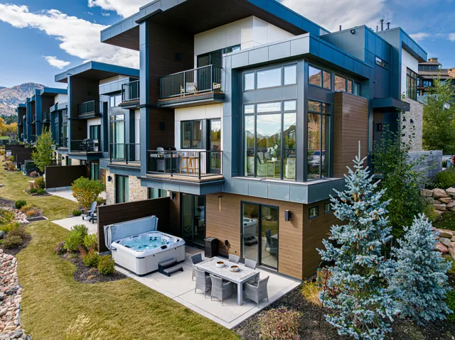 Back of house with a balcony, a patio area, stone siding, and a mountain view
