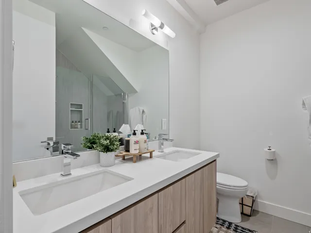 Bathroom with double vanity, light tile patterned floors, and a shower with door