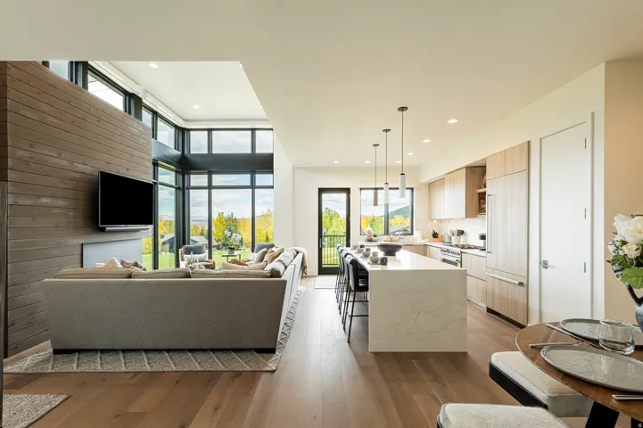 Living room with plenty of natural light, dark wood-style floors, recessed lighting, and a high ceiling