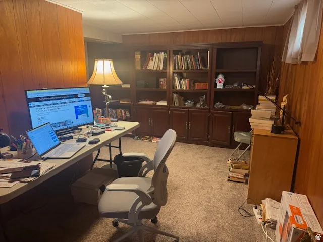Office area featuring wooden walls and light colored carpet