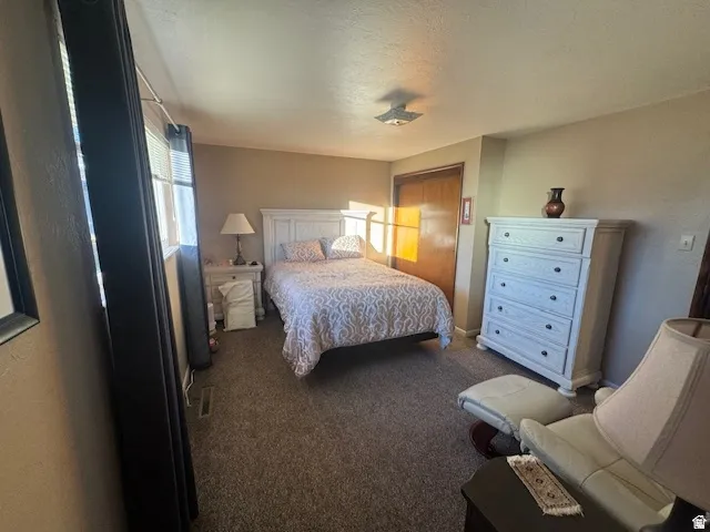 Bedroom with dark colored carpet and a textured ceiling