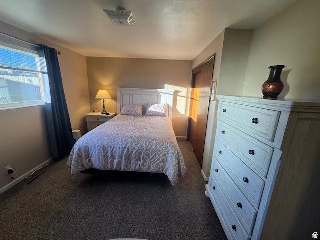 Bedroom featuring baseboards and dark carpet