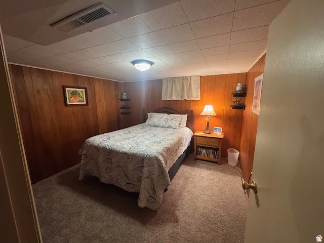 Carpeted bedroom featuring wooden walls