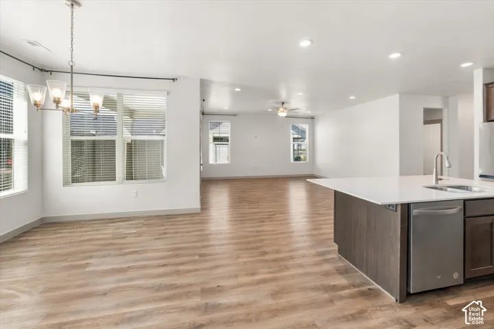 Open-concept living space with wood-finish flooring, recessed lighting, and a kitchen island featuring a stainless steel dishwasher and sink