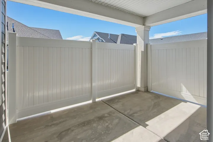 Concrete patio with white privacy fencing and a covered overhead structure