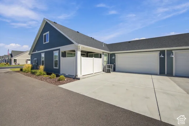 Blue siding exterior with white trim, a covered porch, a concrete driveway, and attached garage doors