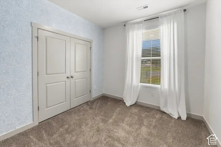 Plush carpet flooring, light blue patterned accent wall, white window blinds, and paneled double doors