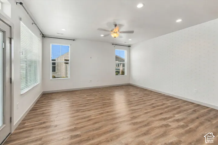 Wood-finish flooring throughout, recessed ceiling lighting, ceiling fan, and multiple windows with blinds