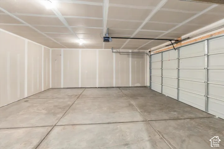 Spacious garage featuring concrete flooring, unpainted drywall, and an automatic garage door opener