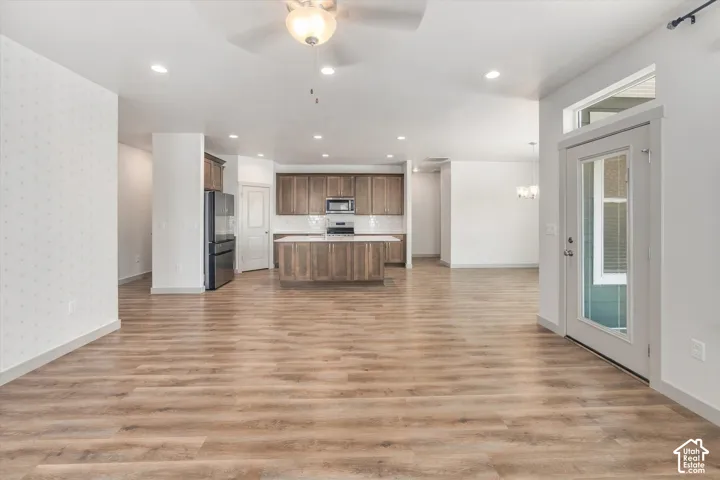 Expansive open-concept living space with wood-finish flooring, recessed lighting, and a ceiling fan