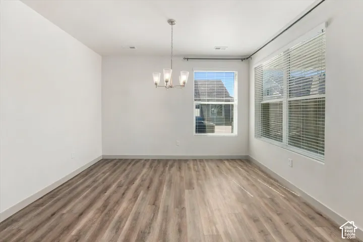 Wood-finish flooring, white walls, and multiple windows with blinds