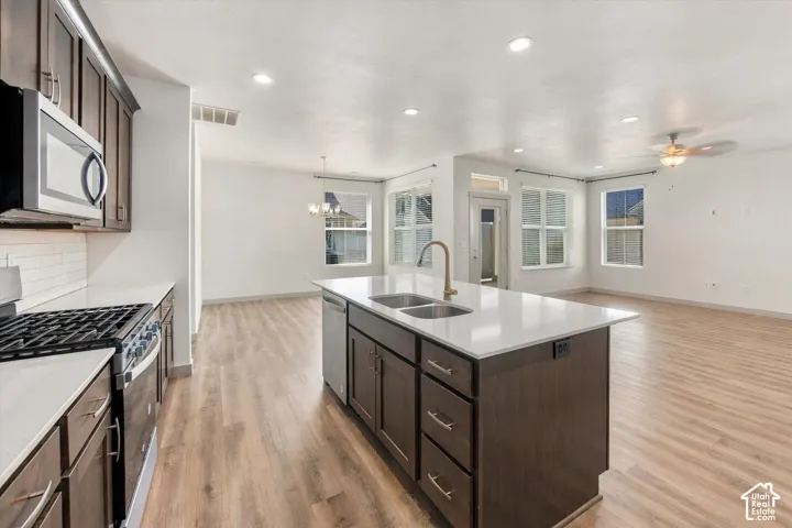 Kitchen featuring a central island with dual sinks, built-in dishwasher, and a bronze-finish faucet