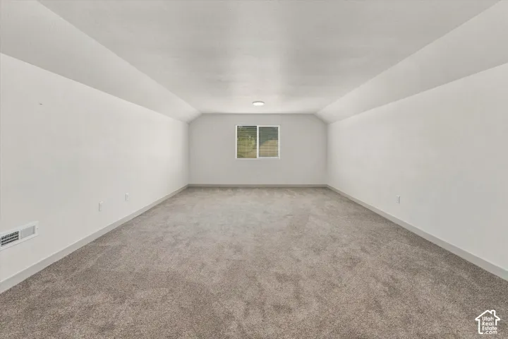 Spacious room featuring neutral carpeting, a single window, white walls, and a flush-mount ceiling light