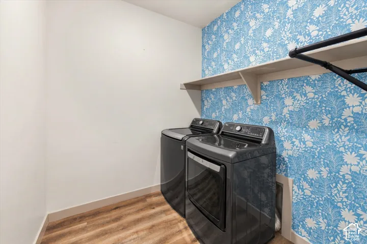 Wood-finish flooring, accent wall with botanical pattern, built-in shelving, and a hanging rod