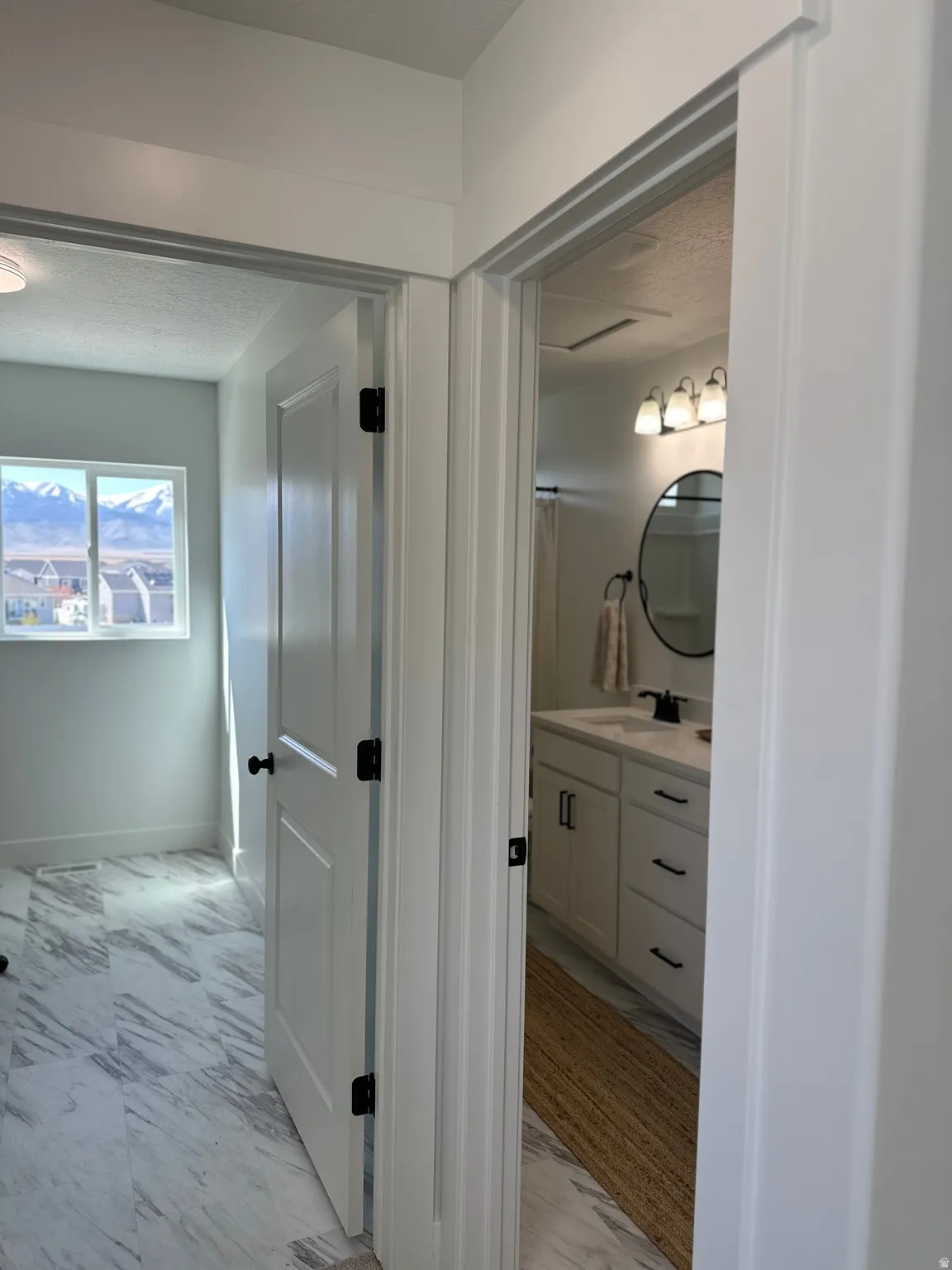 Bathroom with vanity, a textured ceiling, and light marble finish floors
