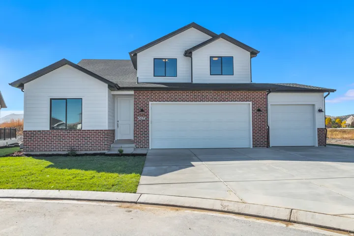 View of front of home featuring brick siding, concrete driveway, a front yard, and a shingled roof