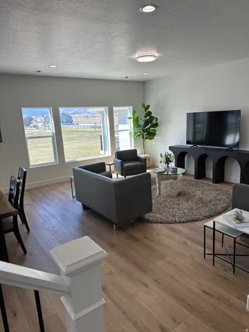 Living room with light wood-style floors, a textured ceiling, and recessed lighting