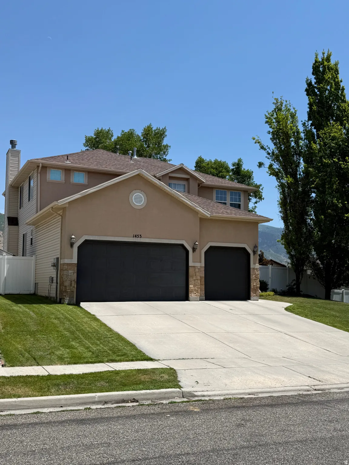 Contemporary residence featuring a two-car garage with stone accents, stucco and siding exterior, and a gabled roof