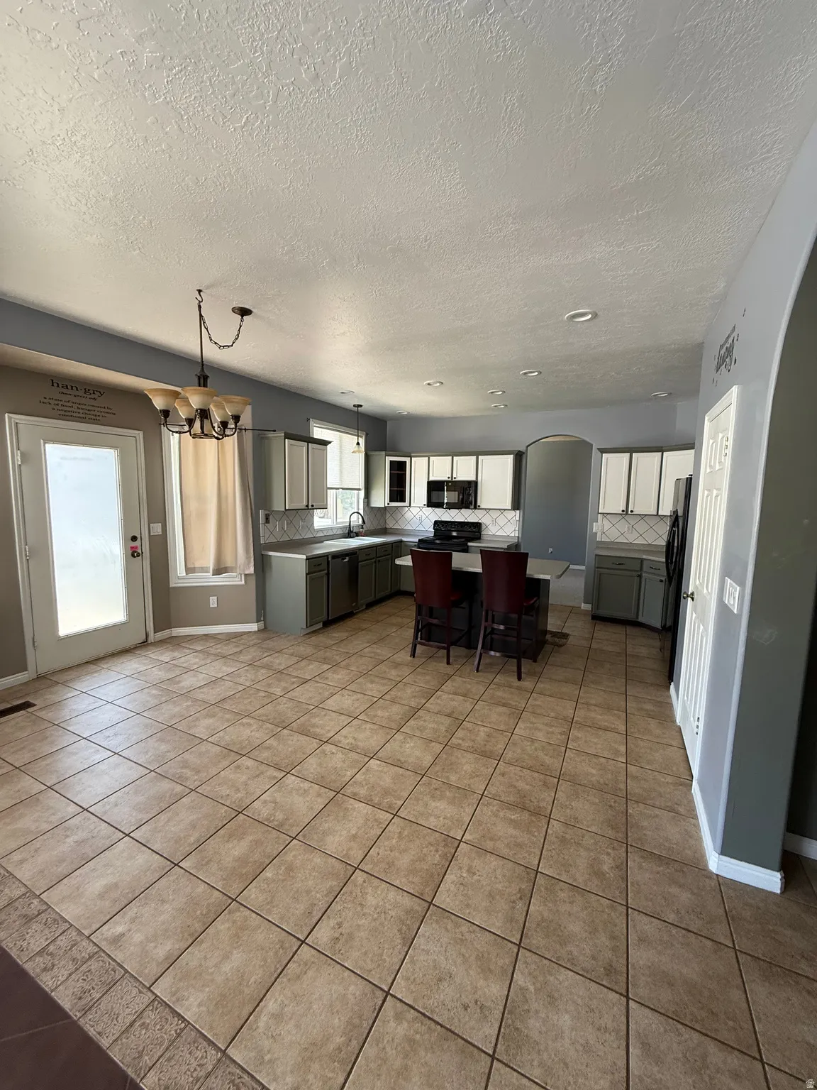 Spacious kitchen featuring tile flooring, a central island with seating, ample cabinetry, and recessed lighting