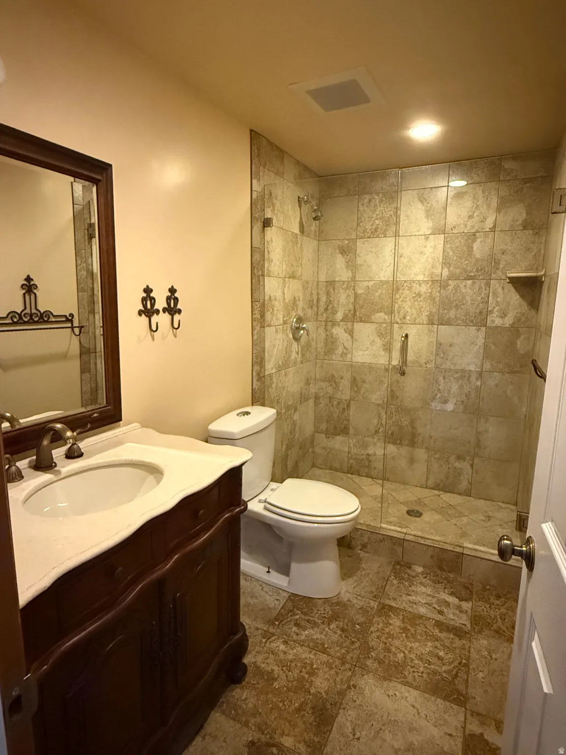 Bathroom with a wood-finish vanity featuring a white countertop and undermount sink