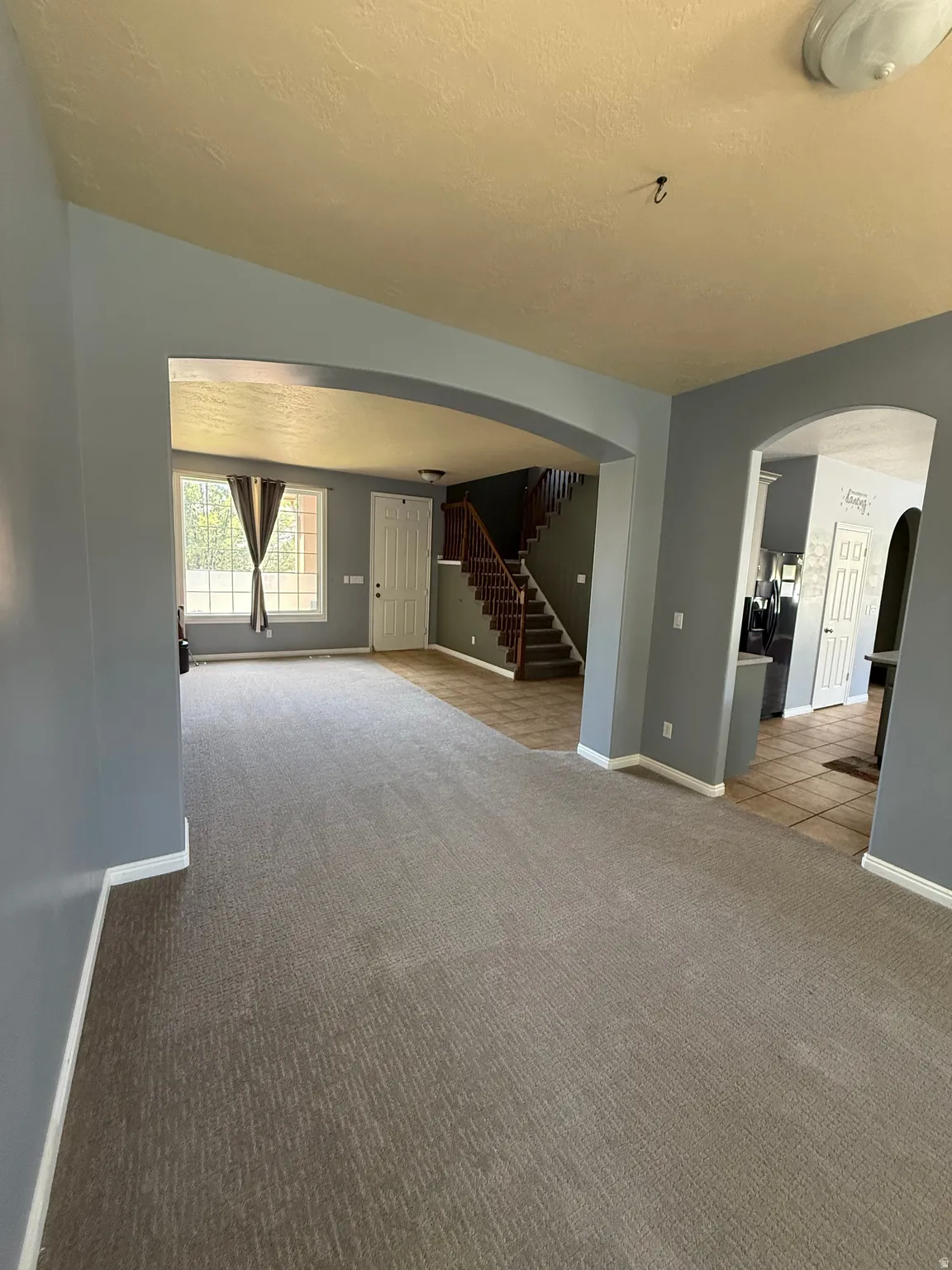 Spacious living area featuring neutral-toned carpeting and light gray walls