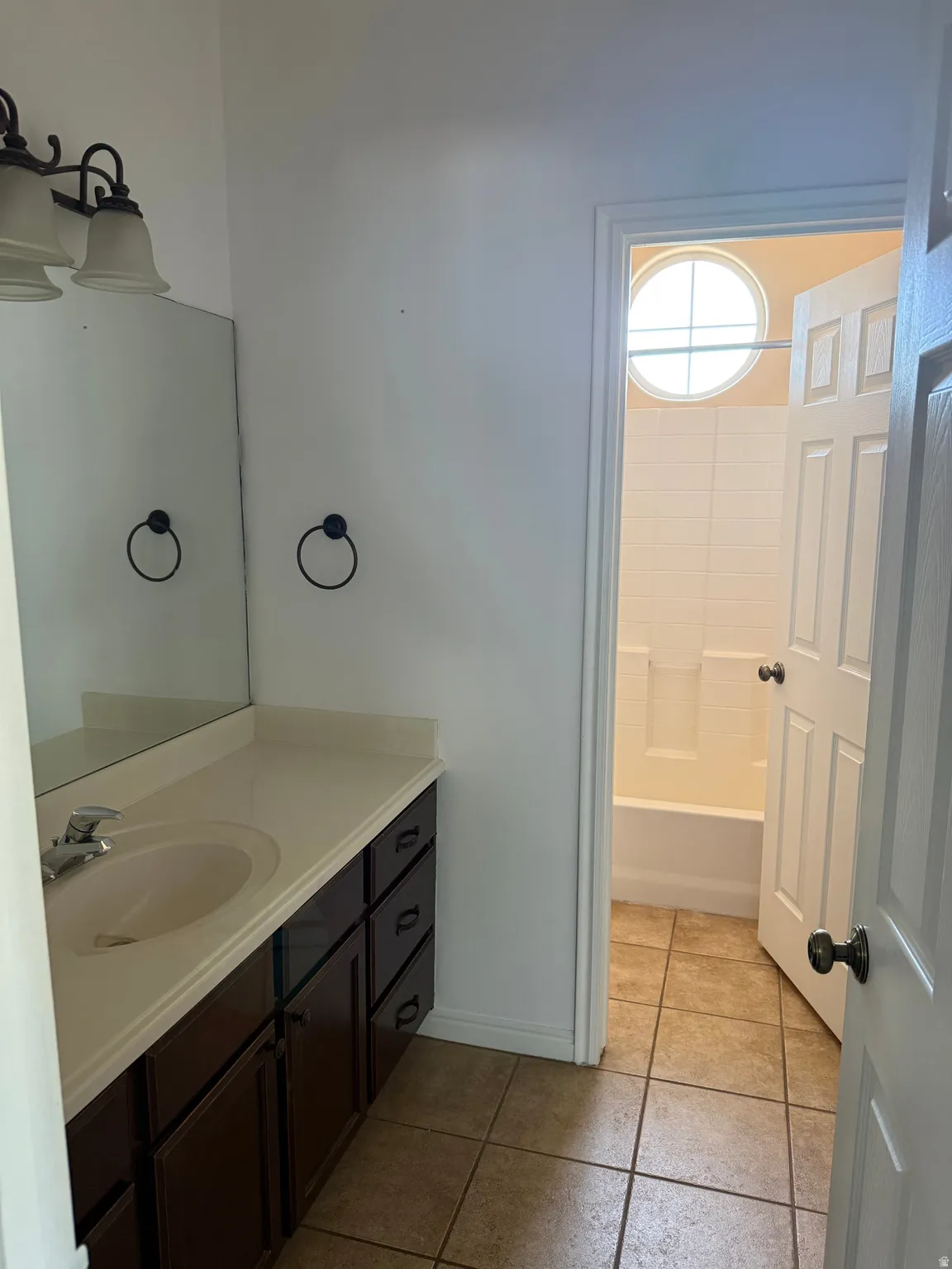 Bathroom featuring a vanity with dark wood-finish cabinetry, a large integrated sink, and a light-colored countertop